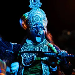An artist's striking portrayal of the goddess, captured at night. The vibrant blue makeup and intricate costume stand out dramatically against the dark background.