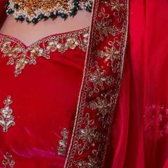 This image highlights the intricate floral gold and silver embroidery on the border of the red velvet lehenga, showing the quality of the outfits I offer for rent.