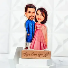 A caricature of a couple in traditional Indian attire, mounted on a wooden stand engraved with "I love you".