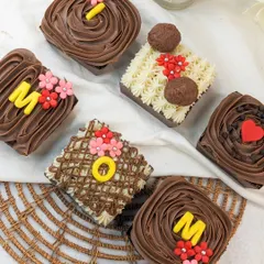A collection of our Mother's Day brownies, each individually decorated with frosting, flowers, and letters spelling out "MOM".