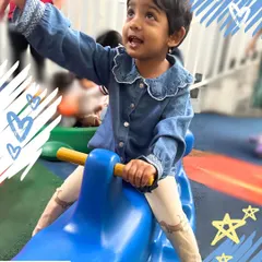 A child enjoys a ride on a rocker in our play area. This simple activity helps develop balance, coordination, and gross motor skills, all while having fun.