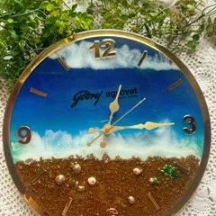 Another angle of the Godrej Agrovet clock, showing the glossy finish and the intricate details of the preserved animal feed that forms the "sand" of the beach scene.