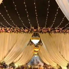 An enchanting wedding mandap setup with a ceiling of fairy lights, elegant white drapes, and beautiful chandeliers, creating a magical ambiance for the ceremony.