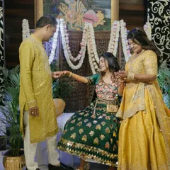 A beautiful family moment during the Mehendi ceremony. The decor, with its intricate wooden screen and floral garlands, provides a warm and traditional setting for these precious interactions.
