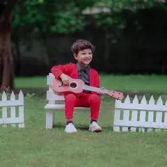 A future rockstar. His joyful smile while strumming a tiny guitar is absolutely infectious. The simple white picket fence and green grass create a perfect stage for his outdoor portrait session.