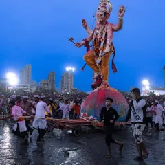 Devotees pull a large Ganesha idol towards the sea for immersion in Mumbai. The image captures the effort, devotion, and festive atmosphere of Ganesh Visarjan.