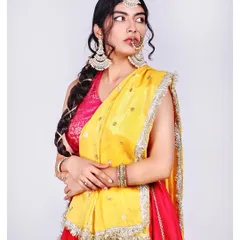 The vibrant contrast of pink and yellow in this traditional attire is the focus here. The clean white background makes the colours pop, while the model's pose highlights the beautiful drape of the dupatta and the statement jewellery pieces.