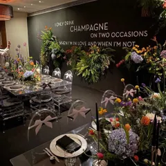 Another angle of the spectacular "Champagne" themed dinner, showcasing the ghost chairs and the lush, wildflower-inspired floral arrangements running down the mirrored table.