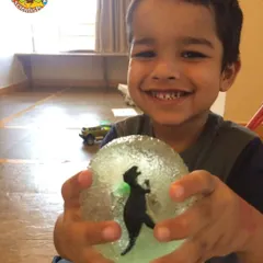 This happy explorer proudly displays a dinosaur he excavated from a gelatin "ice block." It's a fun sensory activity that teaches kids about fossils and excavation.
