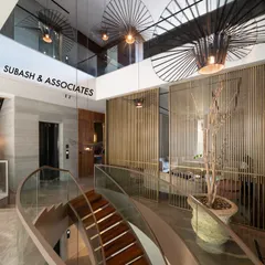 This view from the upper level shows how I design open-plan lobbies to be multi-dimensional. The curved staircase, glass railings, and dramatic pendant lights work together to create a striking focal point that enhances the flow and verticality of the space.