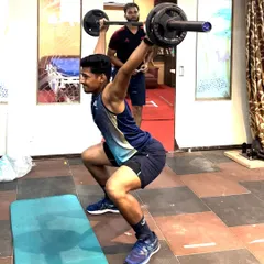 An athlete executes a perfect overhead squat, a challenging movement that tests mobility, stability, and total-body strength. I am observing closely to provide immediate feedback on form.