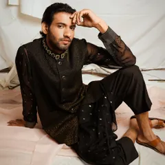 For this menswear look, I focused on creating a contemplative and sophisticated mood. The soft studio lighting highlights the texture of the sheer black kurta and the detailed embroidery on the bandhgala jacket, presenting a modern take on traditional Indian attire.