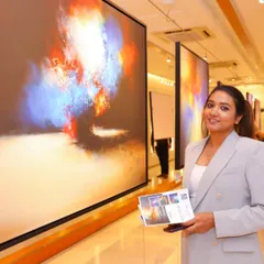 A guest admiring the large-scale, vibrant abstract paintings at the 'Mystic Mirage' exhibition. The gallery's lighting is designed to make the colors pop.