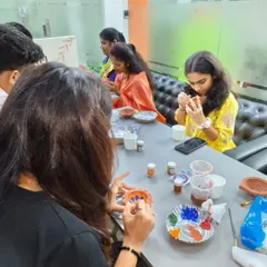 Everyone gets absorbed in their own artistic process. This close-up shows the focus and engagement that pottery painting inspires in a corporate team building setting.