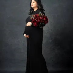 A classic and elegant portrait in a simple black gown. The addition of a deep red bouquet adds a touch of color and sophistication to this timeless maternity photo.