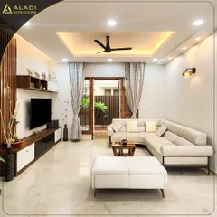 A cozy yet sophisticated living room featuring a comfortable L-shaped sofa, a modern TV unit with wood-fluted paneling, and direct access to a green outdoor space, blending indoor comfort with nature.