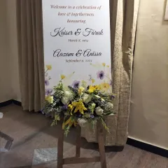Personalized signage adds a special touch to any event. This elegant welcome sign for a 60th anniversary, adorned with a fresh floral arrangement, honors the celebrated couple and welcomes guests to the party.