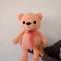 Holding up the handmade pink teddy bear to show its size and cuddly shape.