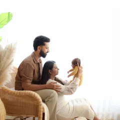 A bright and airy family portrait showcasing the bond between new parents and their baby. The natural light and neutral tones create a soft, warm, and classic look.