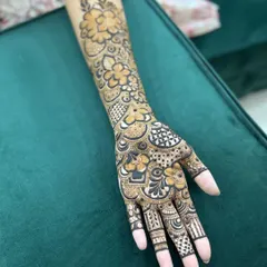 A beautiful full-hand henna design for a bride's sister, featuring a mix of floral patterns and geometric checkers. The design extends up the forearm for a balanced and complete look.