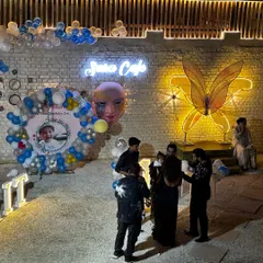 A wide view of a first birthday setup. You can see the custom photo backdrop, balloon decorations, and our signature neon butterfly wall art.
