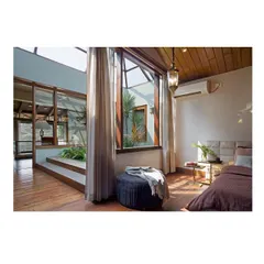 The master bedroom is designed as a peaceful retreat. It directly overlooks an internal courtyard, allowing residents to wake up with a view of nature while maintaining complete privacy. The use of warm wood flooring and a slatted wood ceiling adds to the cozy atmosphere.