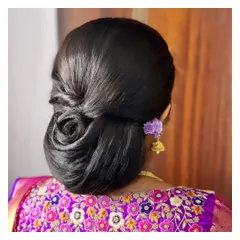A sleek and modern rose bun for Vijayashree. This polished updo is perfect for sarees and lehengas and keeps the focus on the client's face and jewelry.