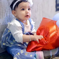 An innocent, curious expression captured in a close-up portrait of a baby girl at her birthday celebration. Kids' photography is about capturing their many moods.
