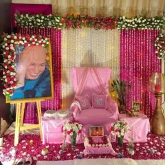 For this Guru Ji birthday event, I created a vibrant pink-themed decoration. The setup includes a portrait on an easel framed with red and white roses, a floor covered in fresh rose petals, and a decorated throne with 'Om' pillows.