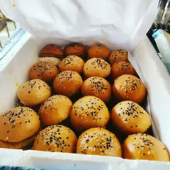 A box of freshly made veg sliders, ready for delivery to a birthday party. Topped with sesame seeds, these mini burgers are a convenient and popular appetizer.