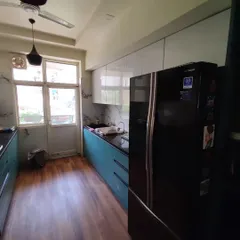 This is a great example of an efficient parallel kitchen layout, perfect for many apartments in Noida. We combined a bold ocean blue laminate on the bottom cabinets with clean, white upper cabinets. This two-tone approach makes the space feel larger while adding a splash of color. The design includes a tall unit to seamlessly integrate the refrigerator.