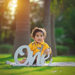 Celebrating one year with a bright and sunny outdoor photoshoot. We use props like this "One" sign to mark the special occasion while capturing your baby's happy personality.