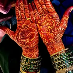 A perfect example of a mature henna stain. The deep red color, paired with traditional green bangles, creates a classic and stunning bridal look.