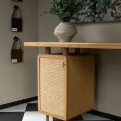 A close-up of a custom-designed desk from our furniture line, House of Goya. The piece features a light wood finish with a caned cabinet door, showcasing our commitment to craftsmanship and timeless materials.