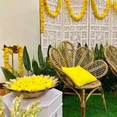 A classic and elegant Diwali setup. We used bright yellow marigolds, traditional brass urlis, and stylish peacock chairs against a carved white screen for a festive feel.