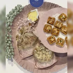 This pastel pink metal platter set is a complete gifting solution. It includes a large tray, a smaller raised platter, dry fruit potlis, and a candle, all customizable in the color of your choice.