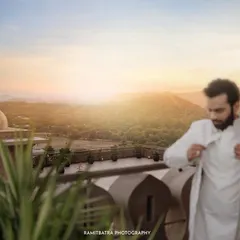 The groom adjusts his sherwani against a stunning sunrise over the Aravalli hills, captured from a balcony at Fairmont Jaipur.