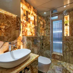 We transformed this space into a breathtaking powder room using floor-to-ceiling backlit Onyx marble. This technique turns the entire room into a statement piece, creating a warm, ambient glow that highlights the natural, dramatic patterns of the stone.