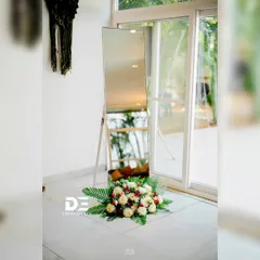 A simple and elegant detail for a Haldi event. A standing mirror is tastefully decorated with a fresh flower arrangement at its base, adding a touch of sophistication to the decor.