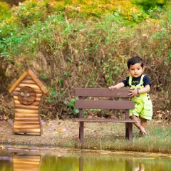 This little explorer is enjoying his outdoor session. I use miniature props like this bench and birdhouse to add a whimsical touch to my kids' photography in natural settings.