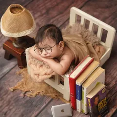 This tiny scholar has fallen asleep on the job! This creative setup with miniature books, a laptop, and glasses is a humorous and adorable theme for a newborn shoot.