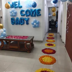 A pathway of colorful flower petal rangolis leading into the house for a 'Welcome Baby' celebration.