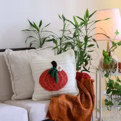 An autumn-inspired pumpkin crochet cushion, adding a touch of seasonal warmth to a simple, elegant sofa. It's a small detail that makes the whole room feel cozier.