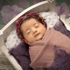 I focus on creating a safe and peaceful environment for your little one. This classic posed newborn portrait captures the serene beauty of a sleeping baby, nestled comfortably in a miniature white cot.