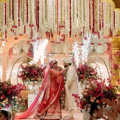 The couple shares their varmala moment under a shower of petals and gentle pyrotechnics. The mandap, with its cascading florals, provides a stunningly romantic frame for this key ritual.