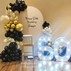 An elegant and sophisticated 50th birthday decoration for a very special celebration. The classic black, white, and gold chrome balloon arch pairs perfectly with the large marquee numbers, creating a timeless and celebratory photo corner.