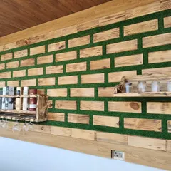 An angled shot of the custom wooden wall installation. This perspective shows the depth of the piece and how the different elements, like the bottle shelf and the smaller spice rack, are integrated into the overall design.