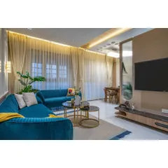 After: Now a chic and inviting living room, complete with layered lighting, sheer curtains, and a curated mix of modern furniture.