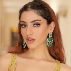 A close-up of the beauty look for a Haldi ceremony. The soft makeup and statement emerald earrings perfectly complement the sunny yellow outfit.