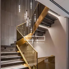Craftsmanship is at the heart of our work. This modern staircase combines sleek dark marble, elegant glass railings with gold accents, and a striking chandelier, turning a functional element into a sculptural centerpiece.